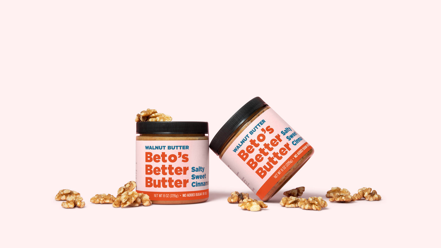 Two jars of Beto's Better Butter surrounded by walnuts